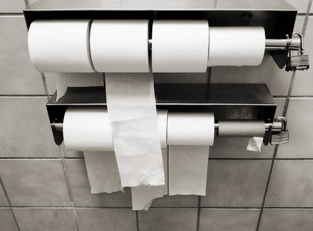 Lockable multi-roll commercial toilet paper dispenser in a public restroom.