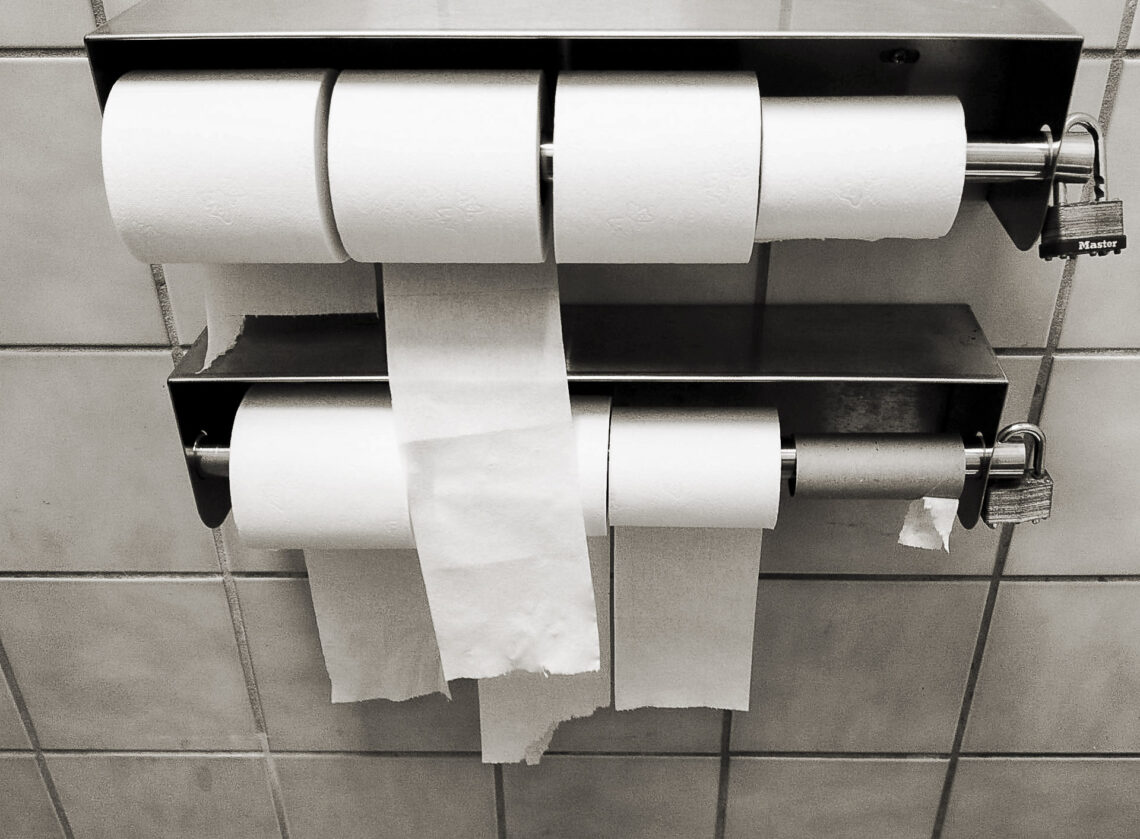 Lockable multi-roll commercial toilet paper dispenser in a public restroom.