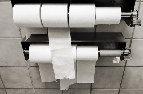 Lockable multi-roll commercial toilet paper dispenser in a public restroom.