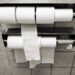 Lockable multi-roll commercial toilet paper dispenser in a public restroom.