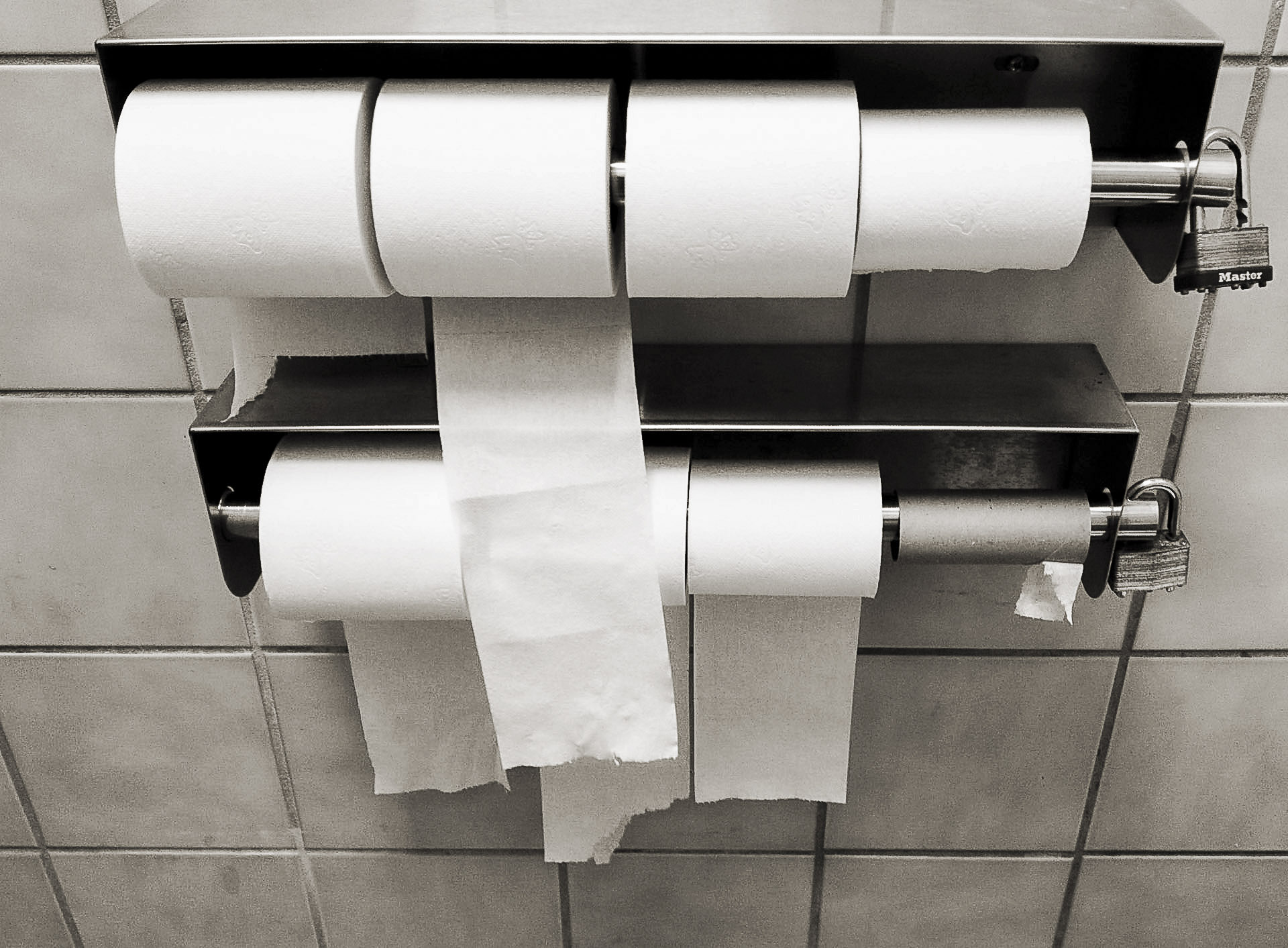 Lockable multi-roll commercial toilet paper dispenser in a public restroom.
