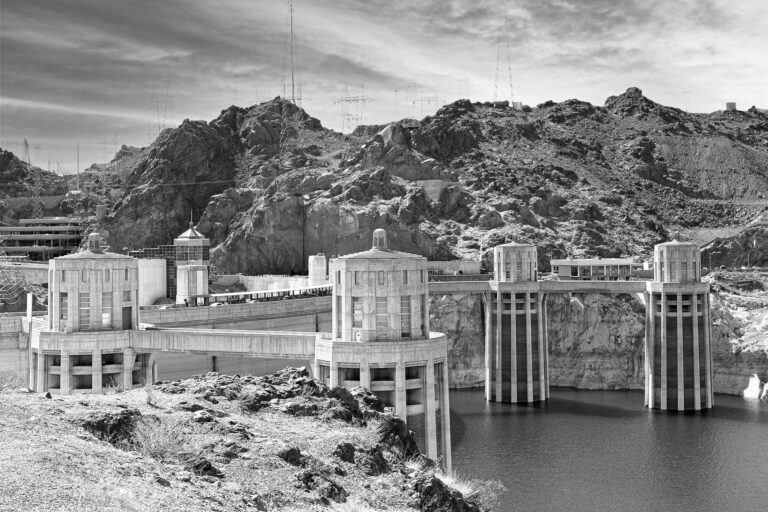 Black-and-white photograph of Hoover Dam's intake towers, Lake Mead, and surrounding rocky mountains.